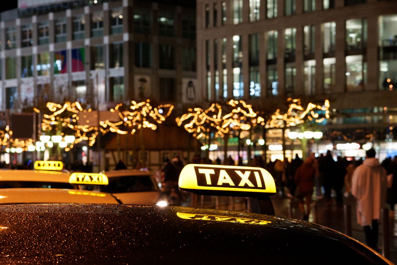 about-img A vibrant city scene at night featuring taxis with illuminated signs and festive decorations.