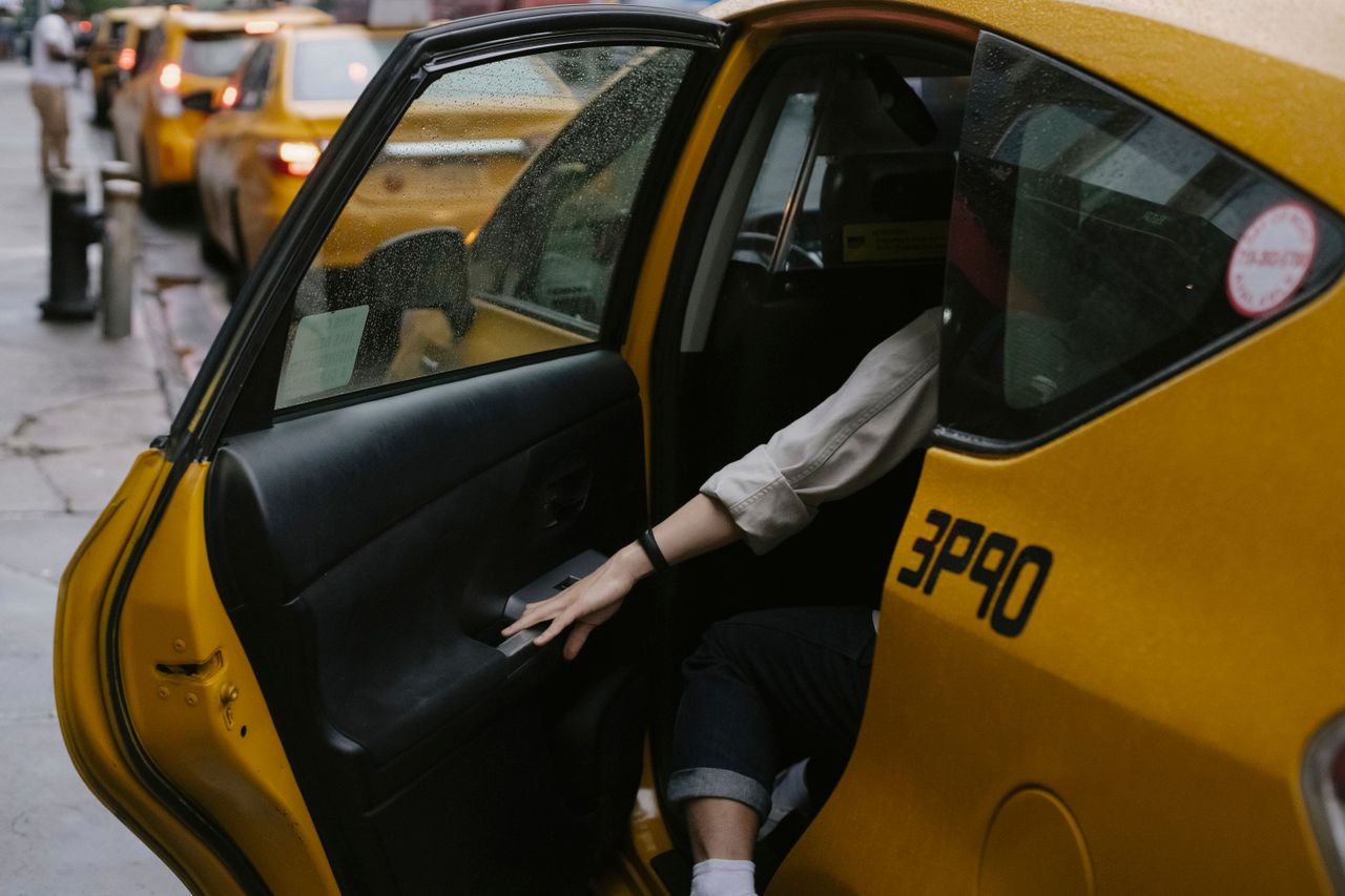 ours-journey Anonymous passenger closing door of cab parked on roadside with blurred cars on background in rush hour on street in city